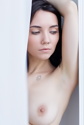 Danniela stands nude behind sheer curtain in bedroom her black hair and tattoos glowing soft light as she poses slowly